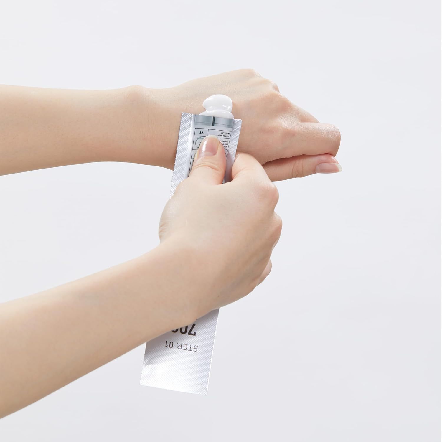 Hände drücken Creme aus einer Tube. Aufdruck: STEP.01 700.