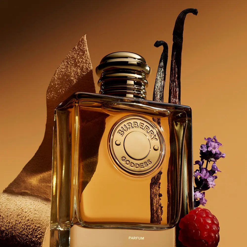 Glasflakon mit Burberry Goddess Logo. Goldfarbener Deckel. Vanilleschoten, Himbeere und Lavendel daneben.