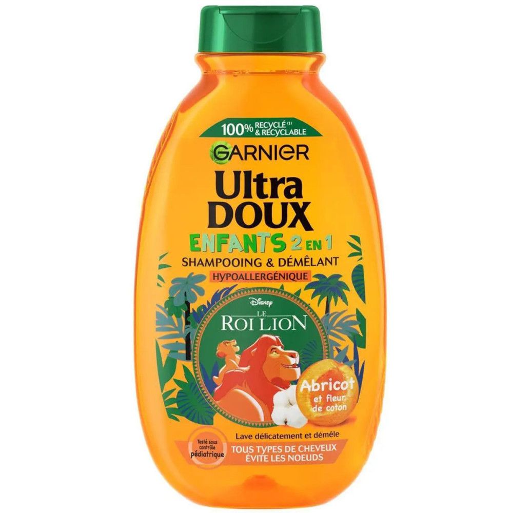 Orangefarbene Shampoo-Flasche mit grünem Deckel. Aufschrift: Garnier Ultra Doux Enfants 2 en 1, Der König der Löwen. Enthält Aprikose und Baumwollblüten.