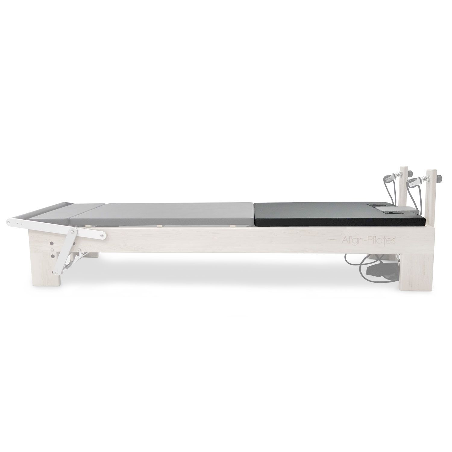 Pilates-Reformer mit schwarzer Matte. Holzrahmen, Seilzüge, und Logo. Graue und schwarze Polsterung. Seitliche Ansicht.