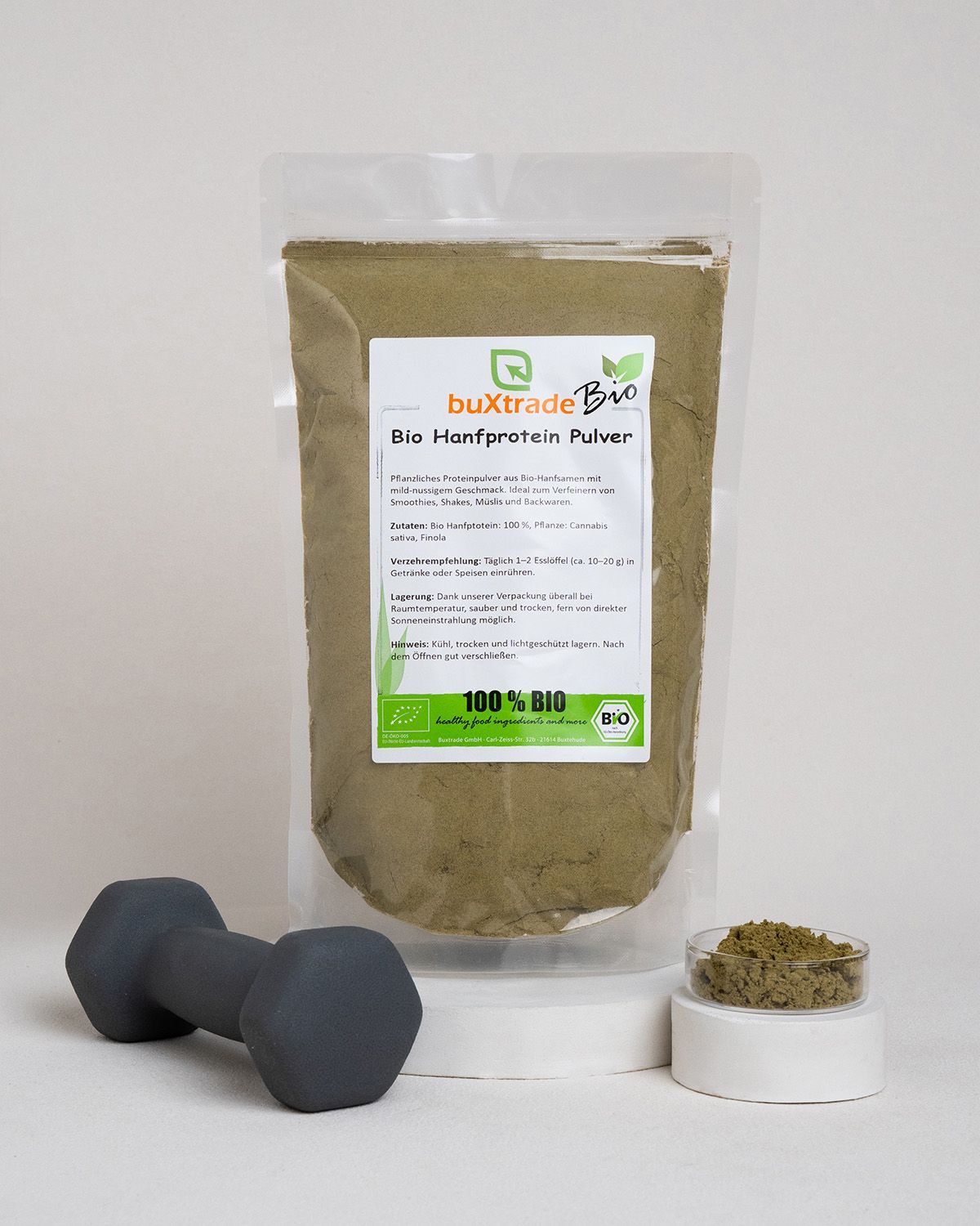 Verpackung von Hanfprotein Pulver neben einer Hantel und einem kleinen Behälter mit Pulver.