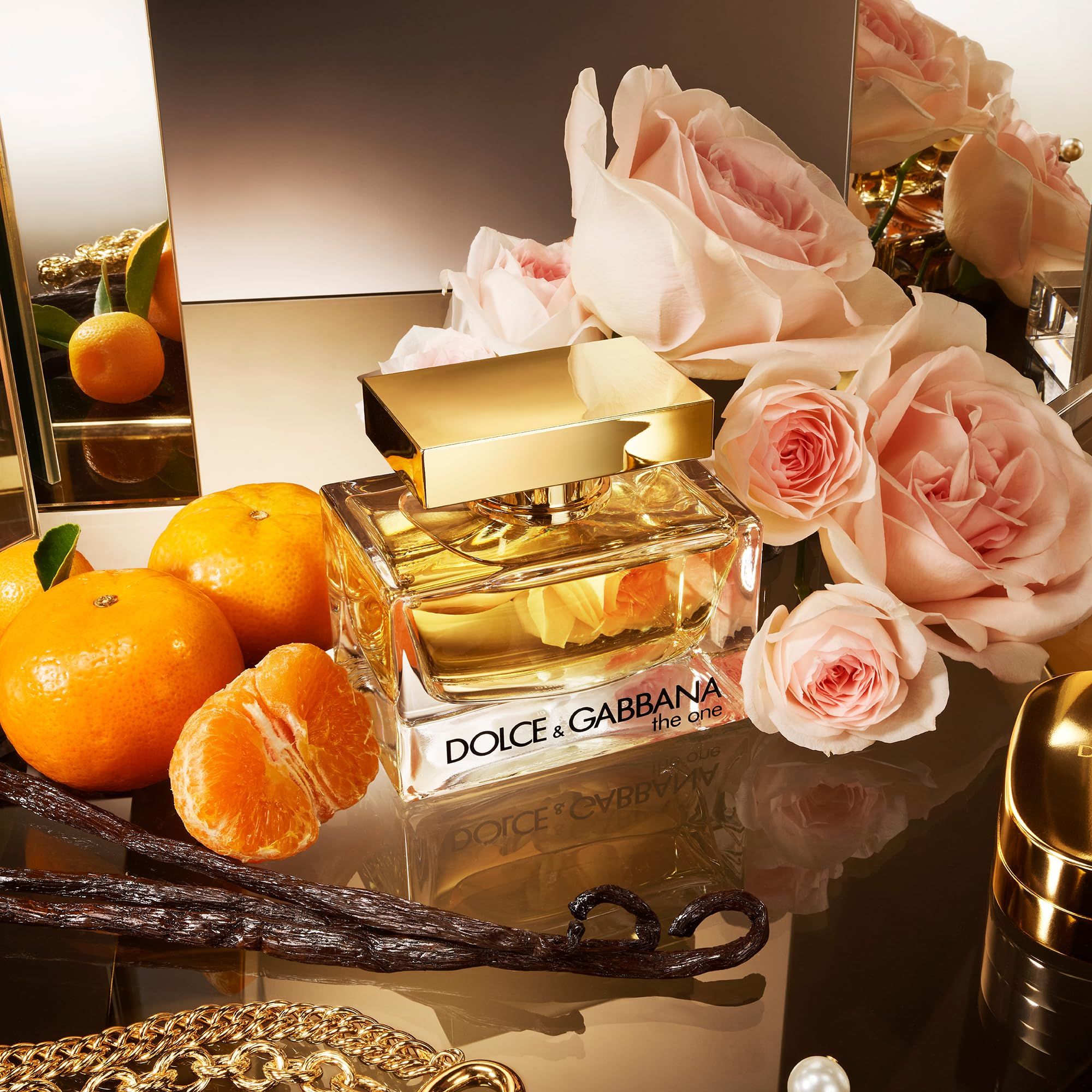 Glasflakon mit goldfarbenem Verschluss, umgeben von Rosen, Mandarinen und Vanilleschoten. Aufschrift: Dolce & Gabbana, the one.