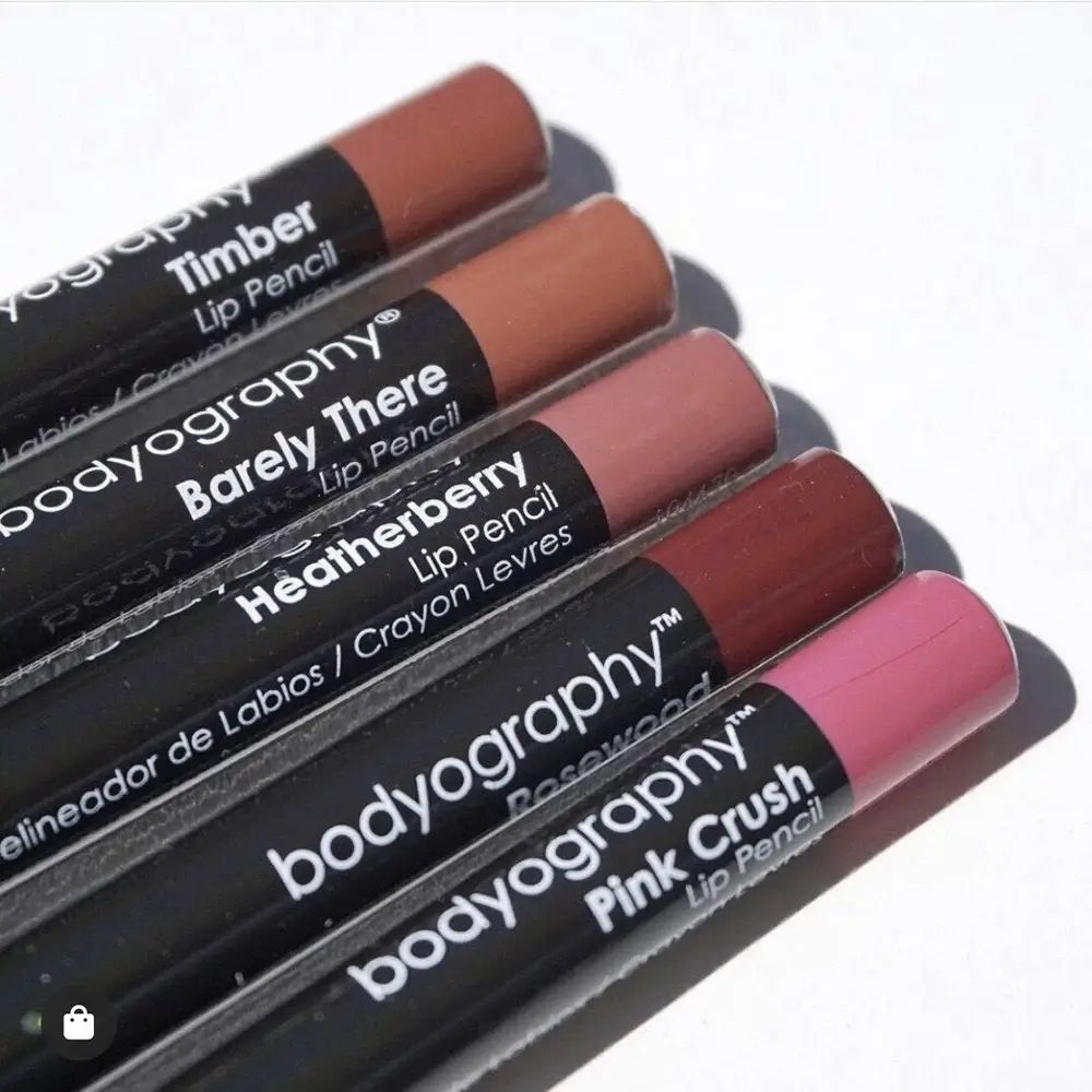 Fünf Lippenstifte nebeneinander. Schwarze Schäfte mit Produktnamen und Farben. Verschiedene Brauntöne.