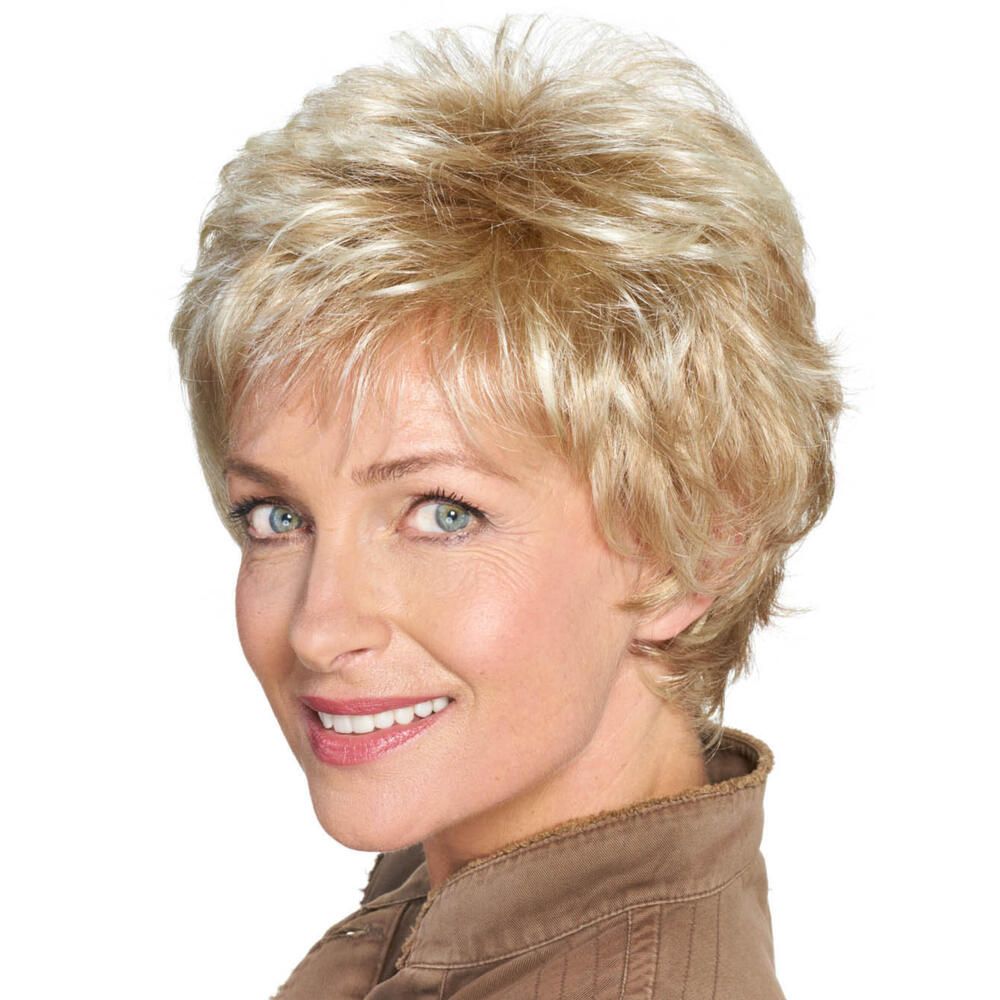 Kurzhaarperücke, blond mit Strähnen, von vorne. Frau mit brauner Jacke, lächelnd.