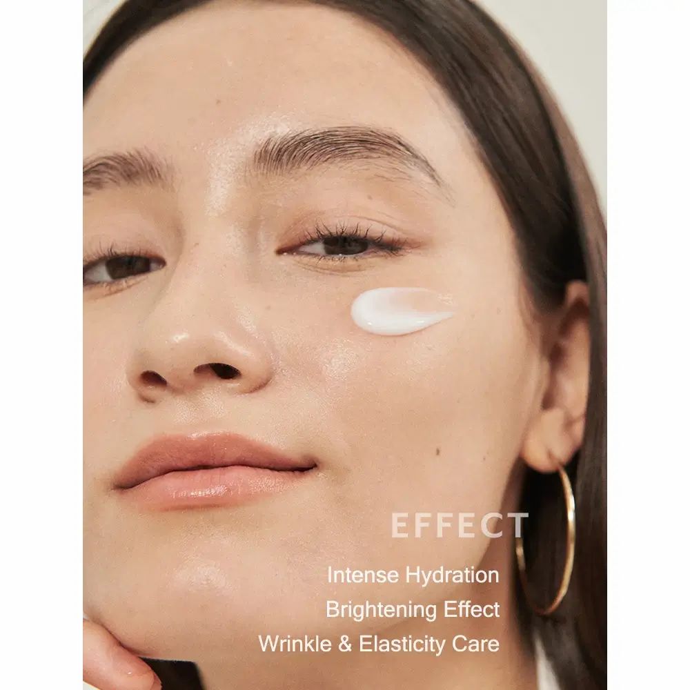 Nahaufnahme eines Gesichts mit Creme auf der Haut. Text: Intense Hydration, Brightening Effect, Wrinkle & Elasticity Care.