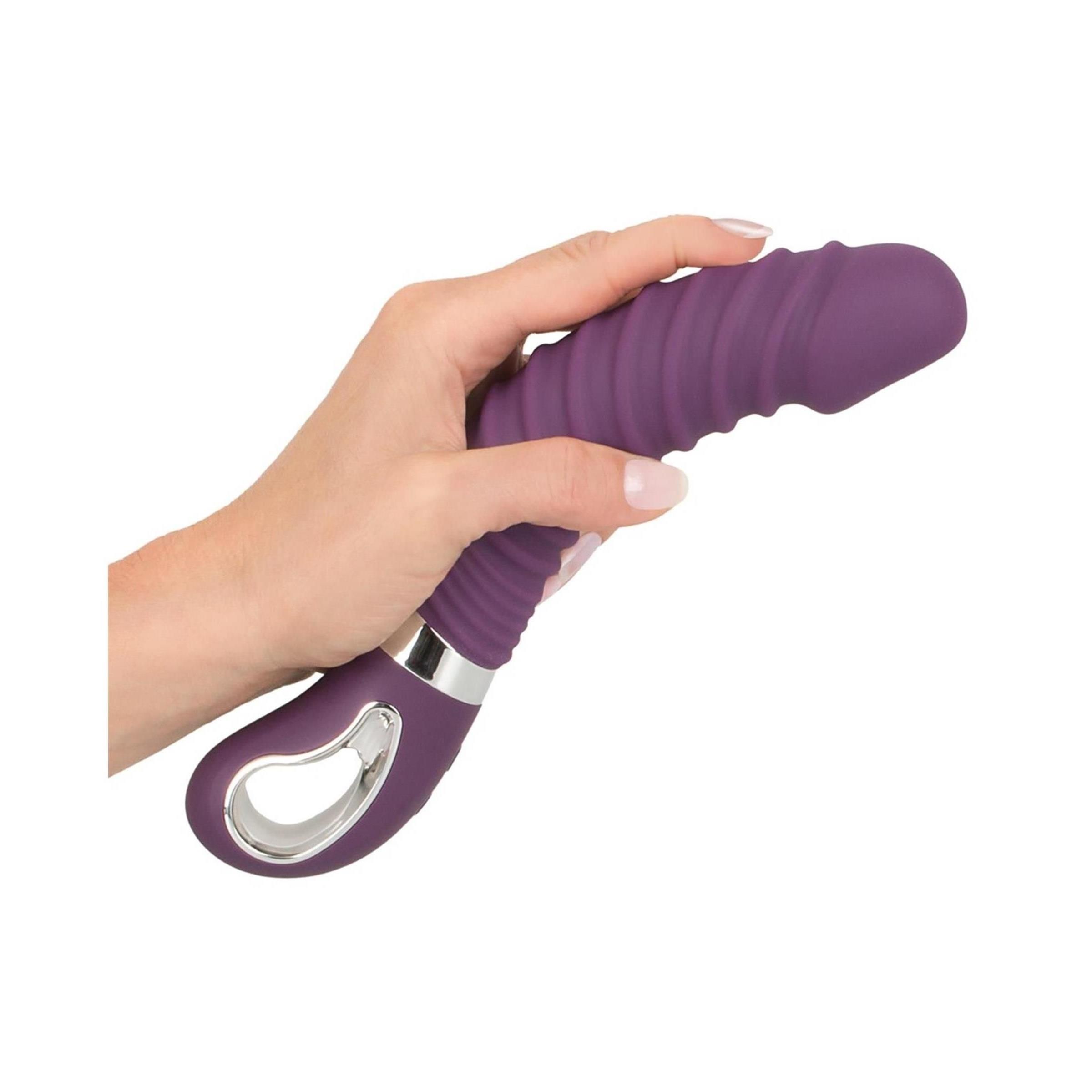 Lila Vibrator in Hand gehalten. Geriffelte Oberfläche, silberfarbener Ring, Bedienfeld. Abgerundete Spitze.