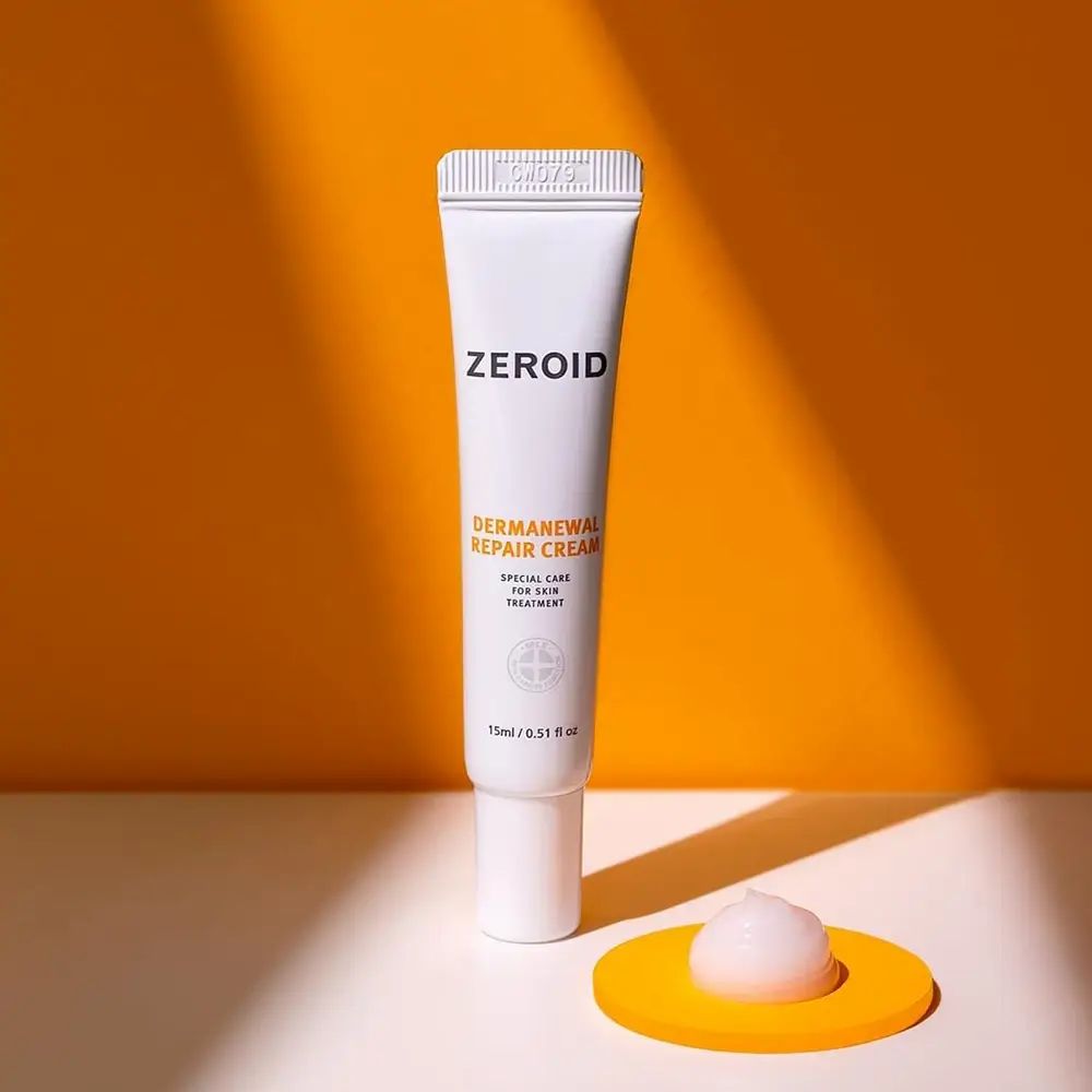 Weißer Cremetube mit Aufschrift: ZEROID, Dermanewal Repair Cream. 15ml/0.51 fl oz. Auf gelber Unterlage.