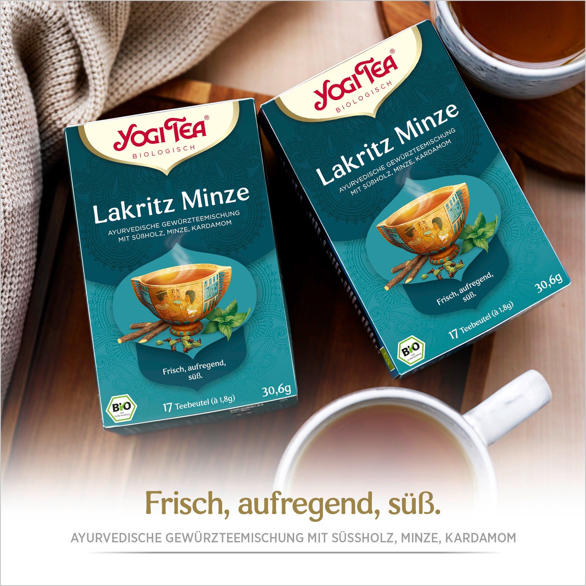 Zwei Packungen Yogi Tea Lakritz Minze auf Holz. Blaue Verpackung mit Logo, Tasse, Kräutern und Schriftzug. Bio-Siegel.