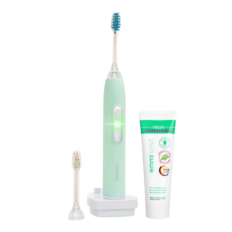 Zahnbürste, Ladestation, und Zahnpasta. Zahnbürste pastellgrün, Zahnpasta mit grünem Streifen. emmi-dent Logo sichtbar.