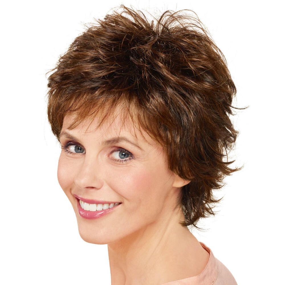 Kurzhaarperücke in Braun mit fransigem Schnitt. Frau mit Perücke lächelt, Blick zur Seite. Helle Haut, rosa Oberteil.