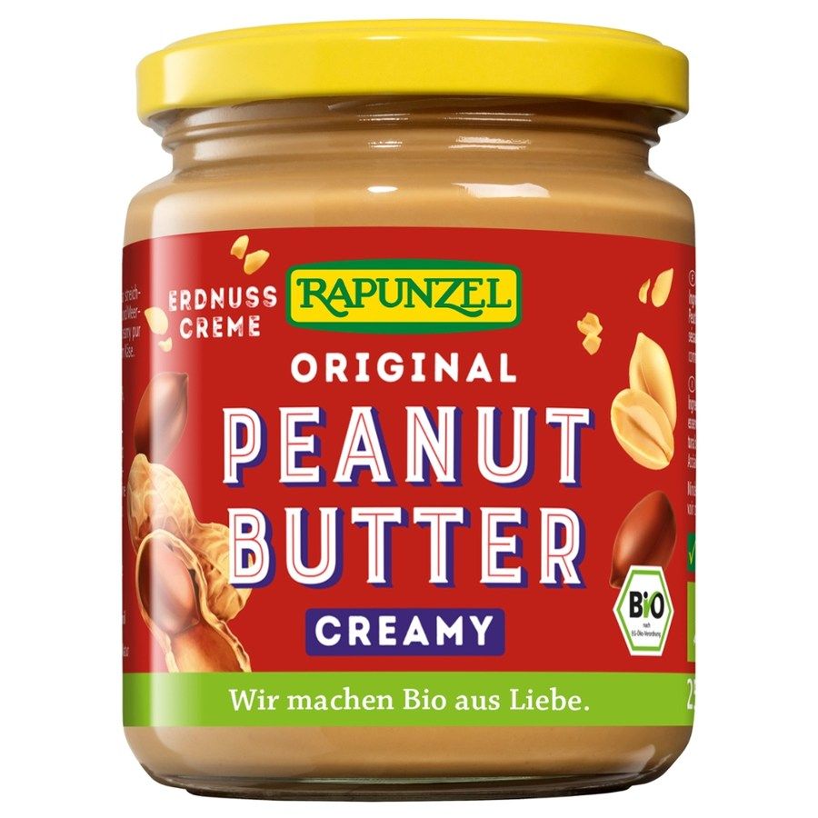 Glas mit Rapunzel Erdnussbutter, cremige Konsistenz. Roter Hintergrund mit Schriftzug "PEANUT BUTTER" und Bio-Siegel.