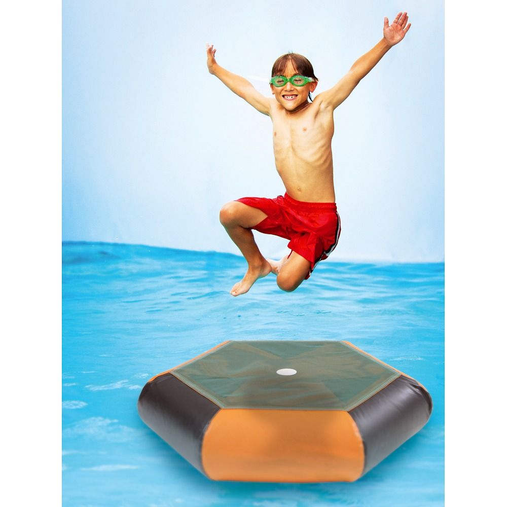 Kind springt über ein sechseckiges Trampolin im Wasser. Grüne Sprungfläche, schwarzer Rand und orangefarbene Seitenwand.