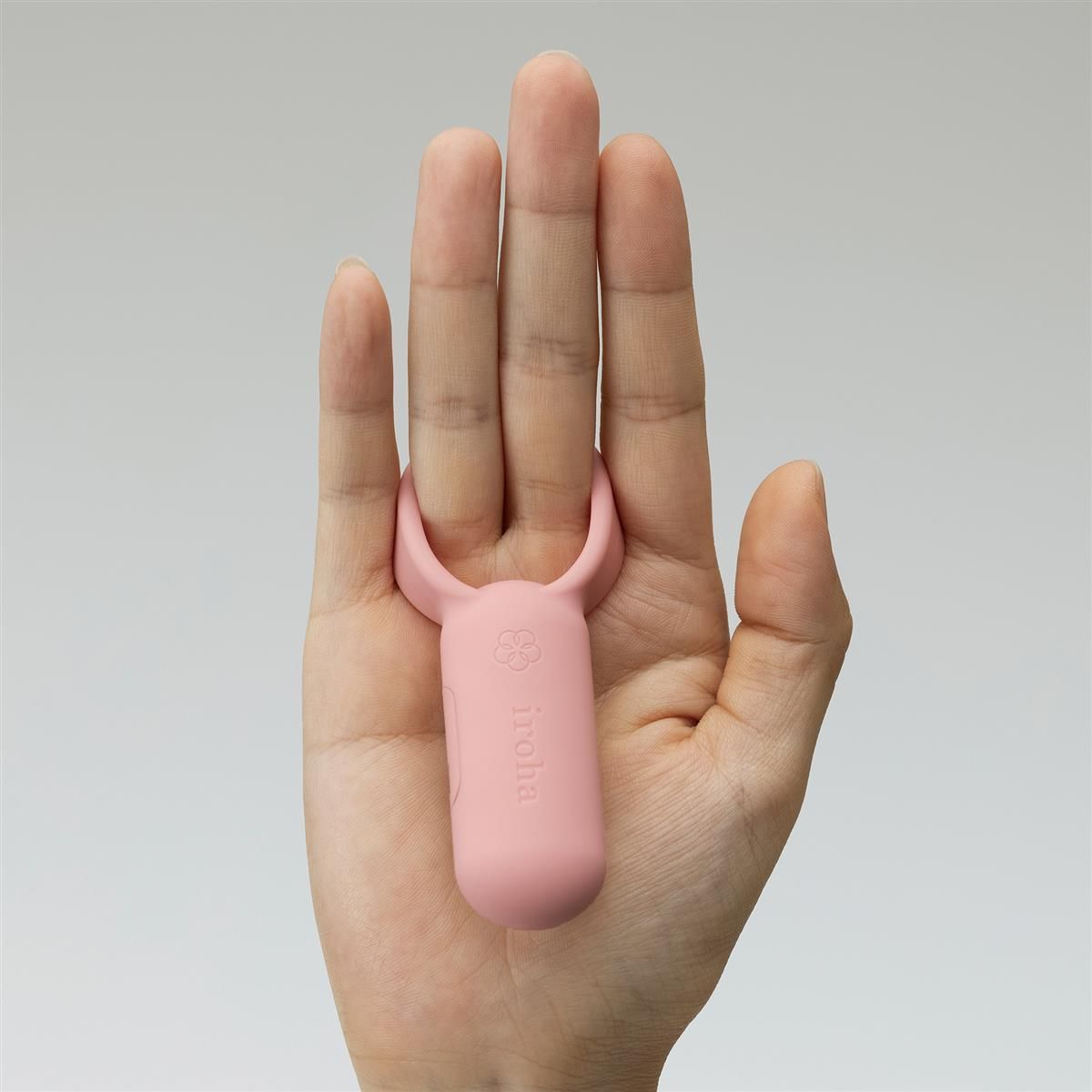 Korallenroter Paarvibrator in einer Hand. Marke iroha. Blütenlogo. Nahaufnahme.