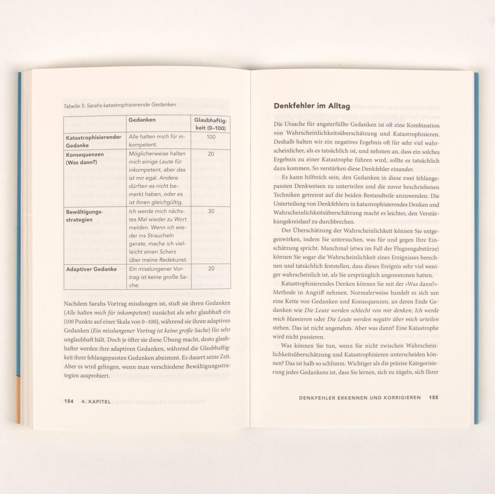 Buch aufgeschlagen, Text in deutscher Sprache. Tabelle mit Gedanken und Strategien. Kapitel: Denkfehler im Alltag.