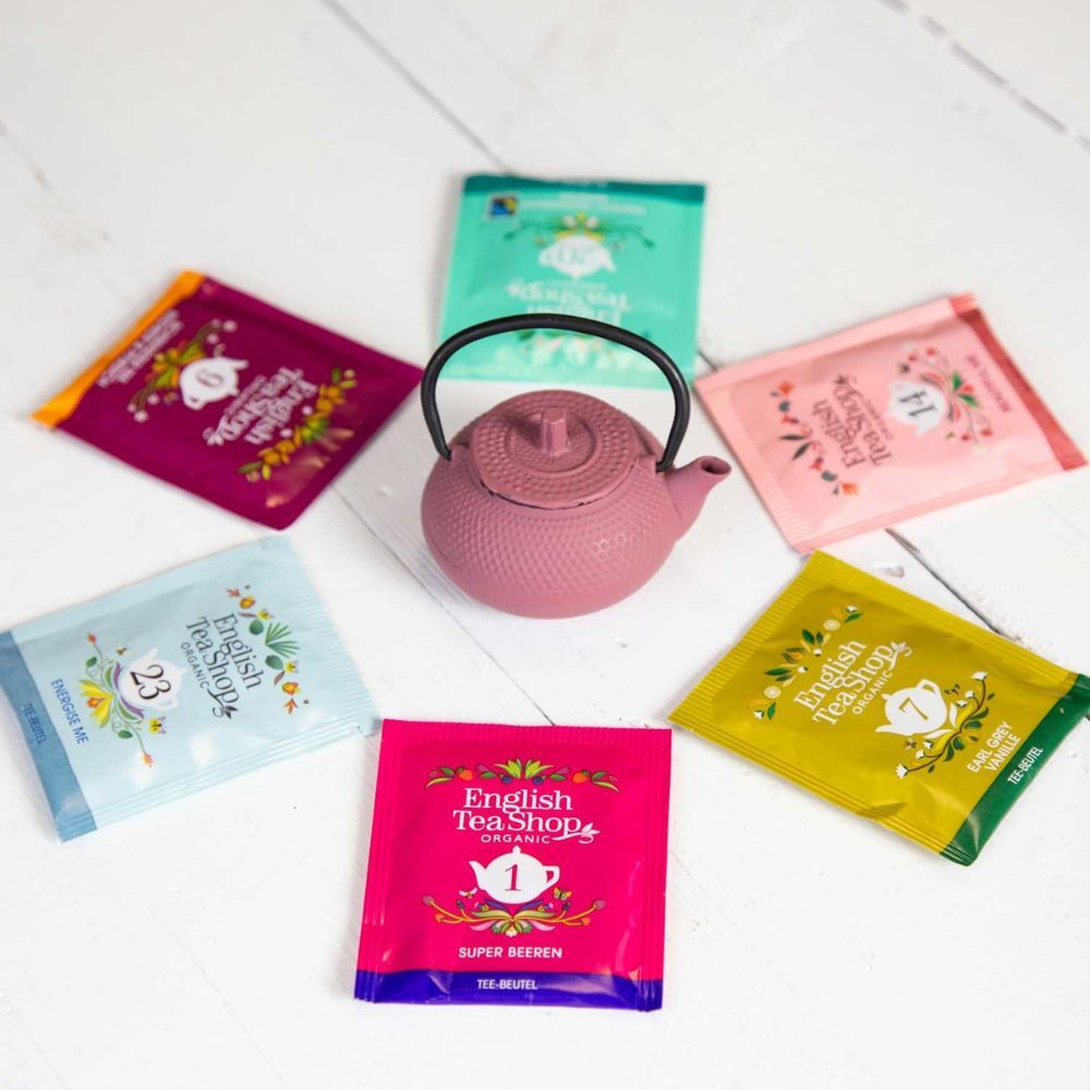Rosa Teekanne mit 6 Teebeuteln. Aufschrift auf den Teebeuteln: English Tea Shop. Verschiedene Farben und Nummern.