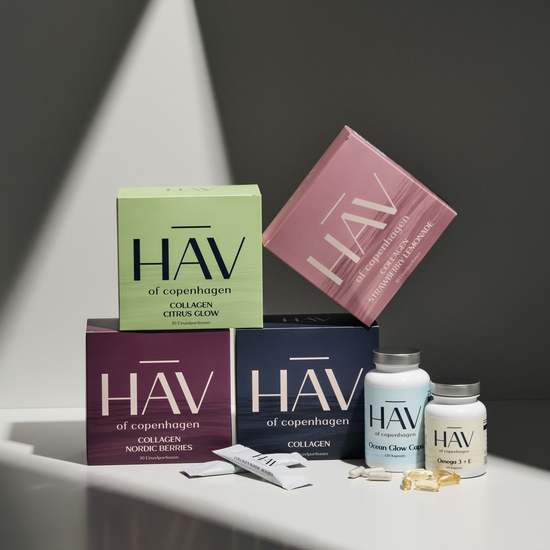 Mehrere Produktverpackungen und Flaschen. HAV Collagen, Omega 3 + E. Verschiedene Farben und Formen.