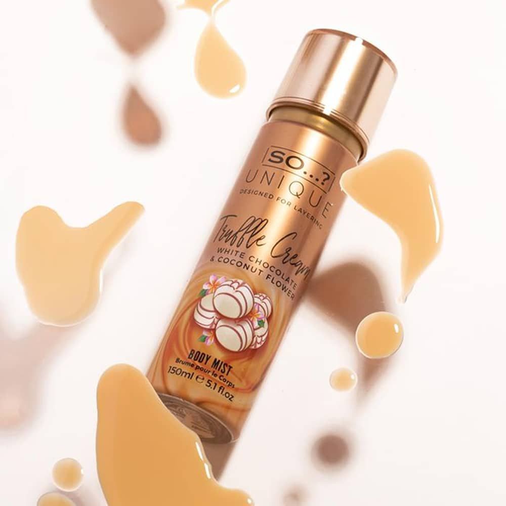 Körperspray. Goldfarbene Sprühflasche mit Aufschrift. Trüffelcreme-Design mit weißen Schokoladenstücken. Flüssigkeitstropfen.