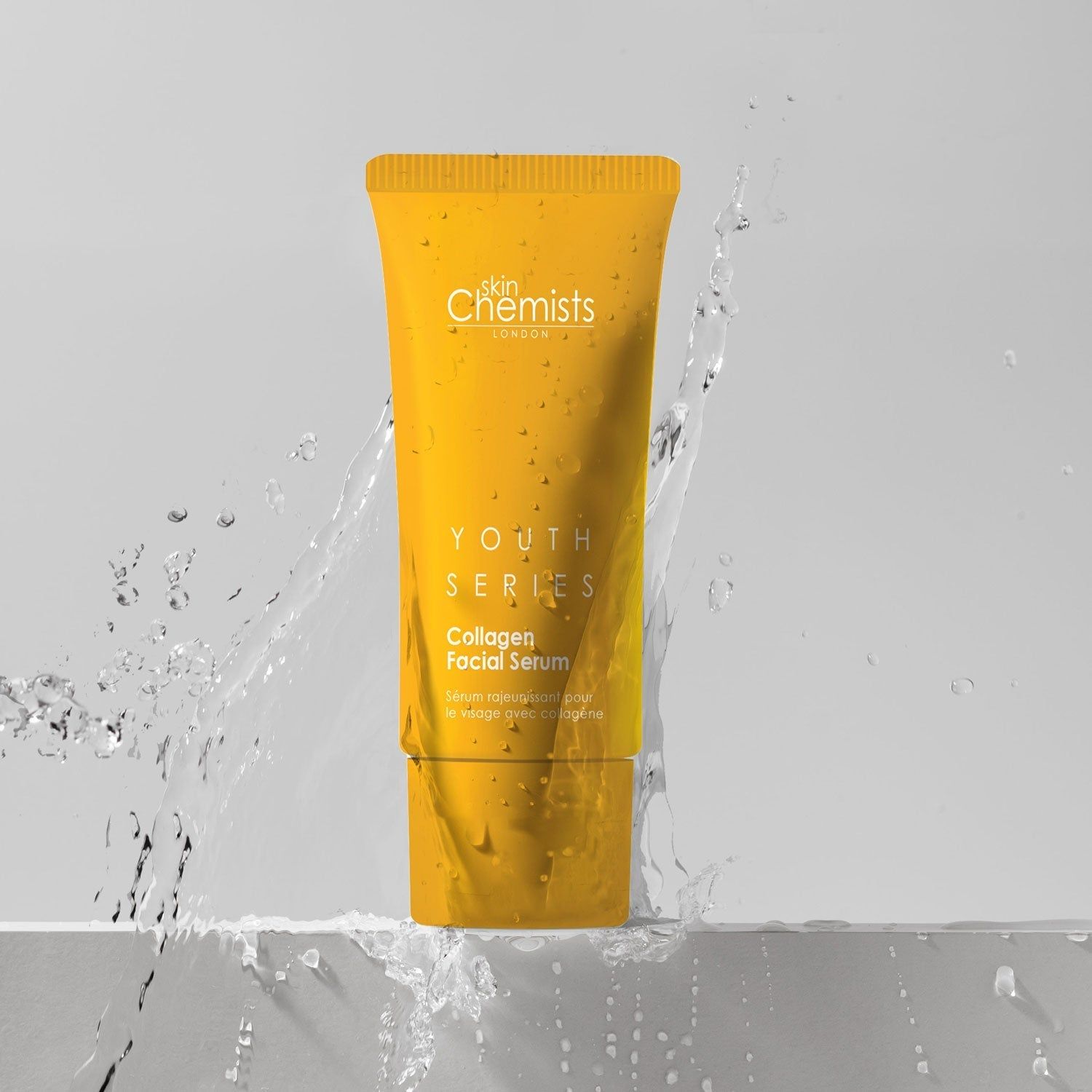 Gelbe Tube mit "skinChemists" und "Youth Series Collagen Facial Serum" im Wasser. Spritzer.