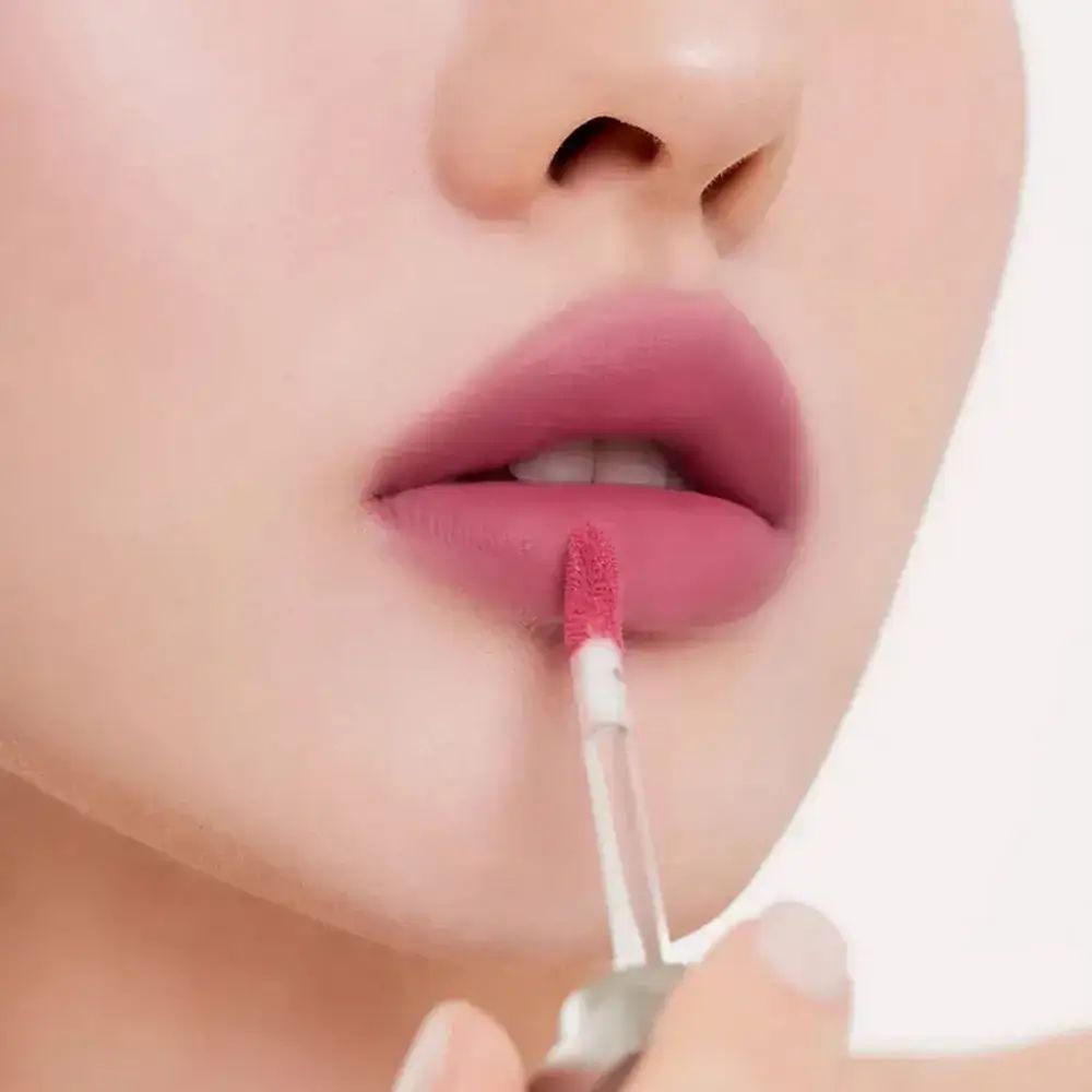 Lippen mit rosafarbenem Lippenstift. Applikator in der Hand. Nahaufnahme.