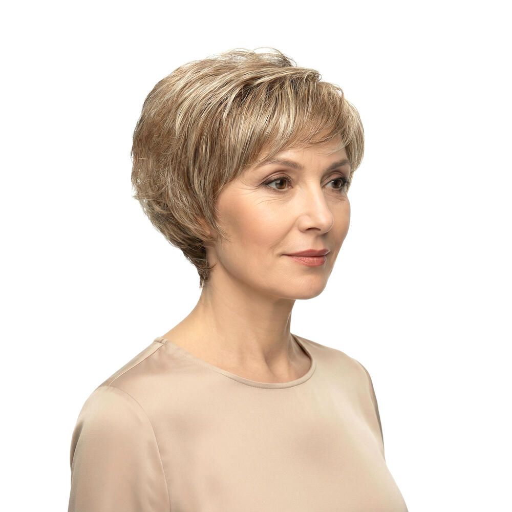 Seitenansicht einer Frau mit kurzer, blond gefärbter Perücke. Beige Oberteil.
