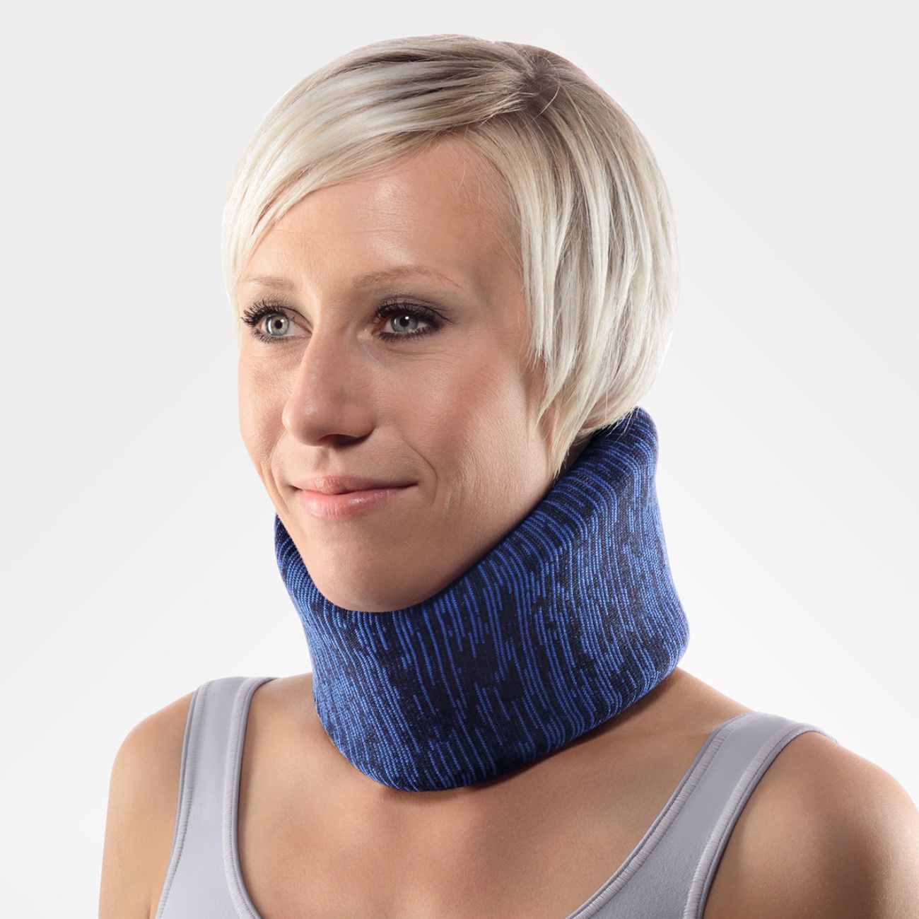 Blau-schwarze Halskrause um den Hals einer Frau. Die Frau trägt ein graues Tanktop. Der Hintergrund ist weiß.