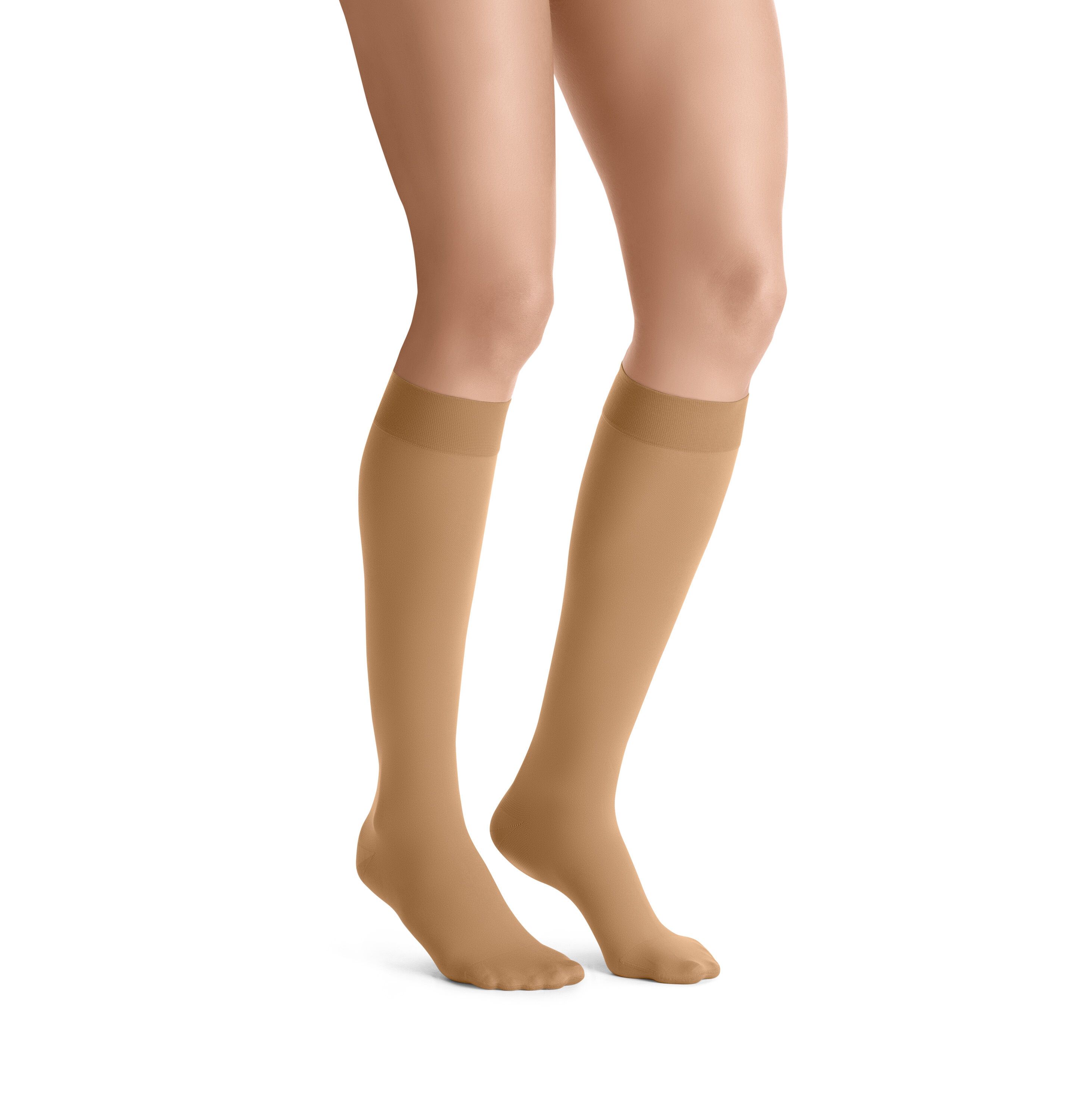 Hautfarbene Kompressions-Kniestrümpfe. Die Strümpfe bedecken die Füße und reichen bis zum Knie. Sie sind an den Beinen einer Person zu sehen.