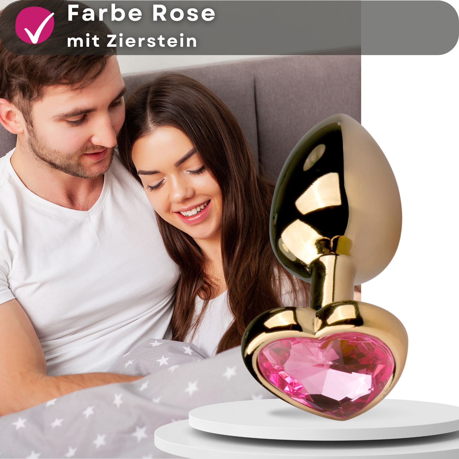Goldfarbener Analplug mit herzförmigem Zierstein. Paar im Bett, Produkt auf Podest.