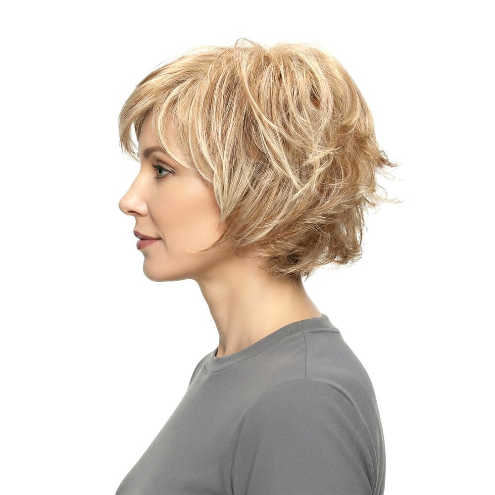 Blonde Perücke mit kurzem, gestuftem Schnitt. Die Frau trägt ein graues T-Shirt. Seitenansicht.