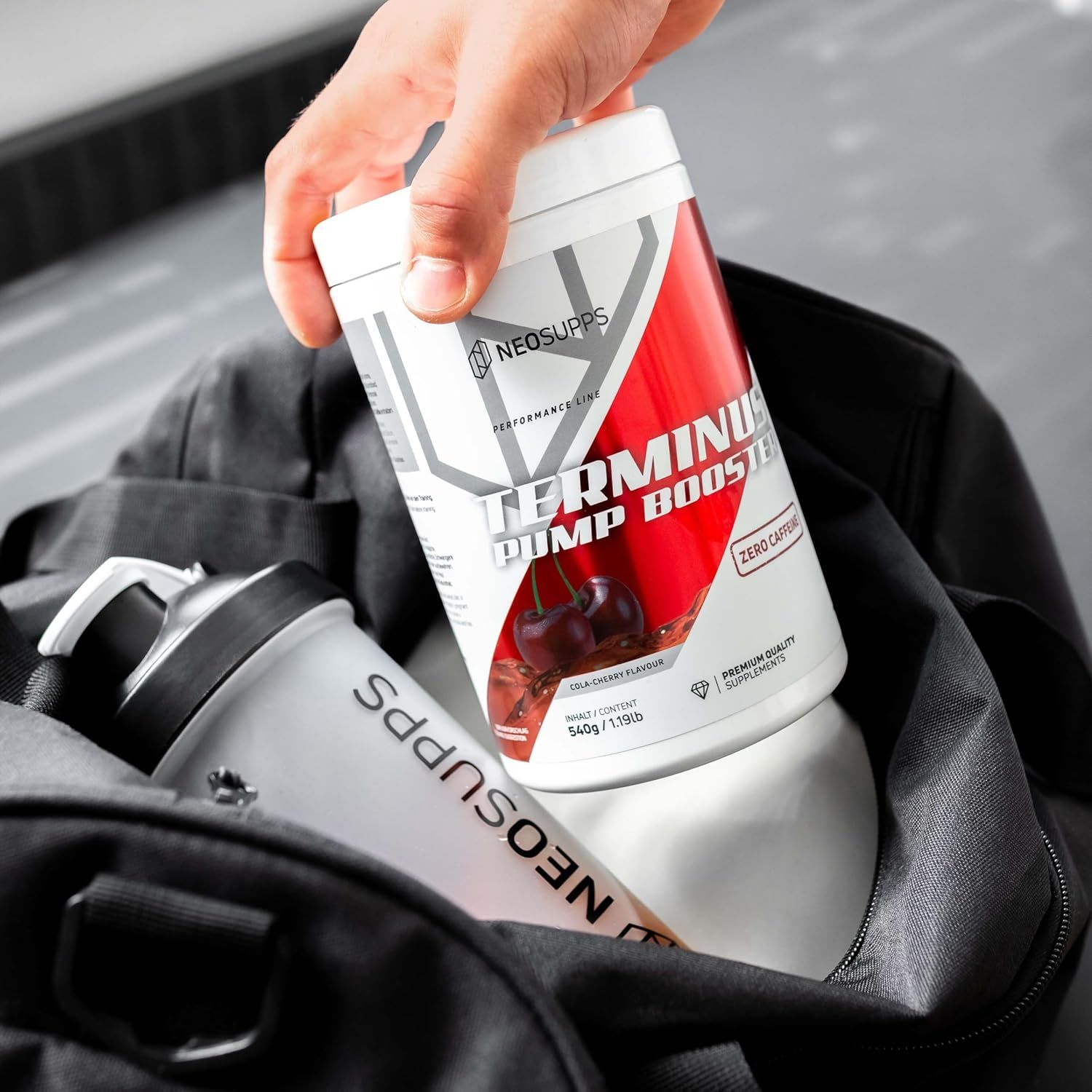 Weißes Supplement-Behälter mit rotem Akzent. Aufschrift: Terminus Pump Booster. In einer Sporttasche.