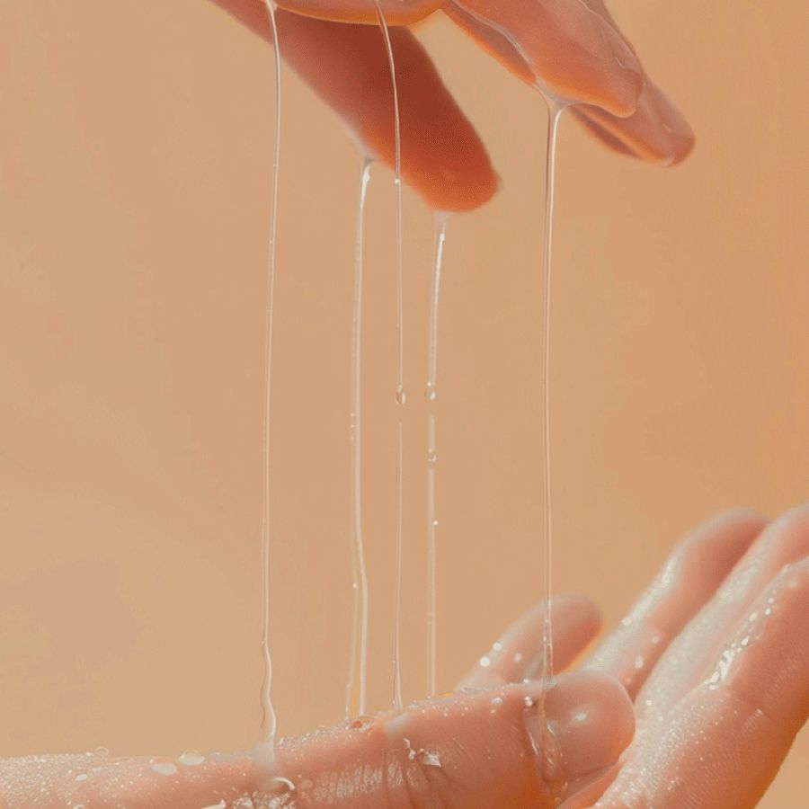 Hände mit transparentem Serum. Das Serum tropft von den Fingern.