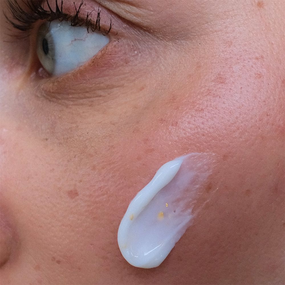 Hautpartie mit aufgetragener Creme. Creme mit goldenen Partikeln. Produktname und Marke nicht sichtbar.