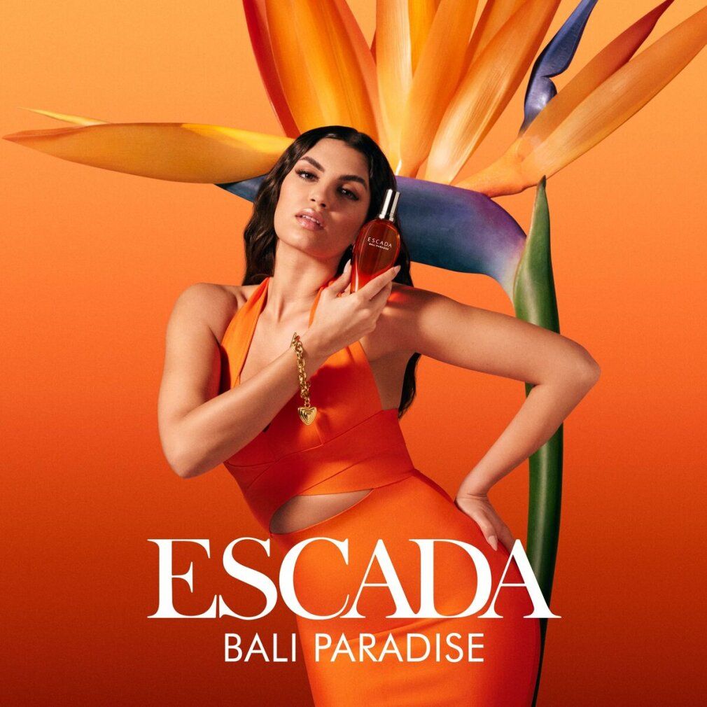 Werbung für Escada Bali Paradise. Frau hält Flakon. Orangefarbener Hintergrund mit Blumen. Schriftzug: Escada Bali Paradise.