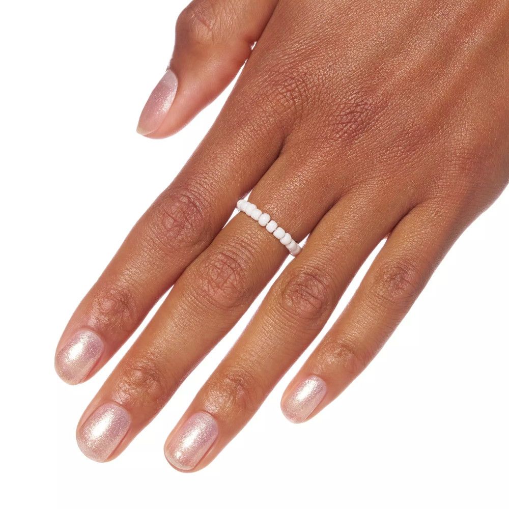 Hand mit Nagellack, rosa schimmernd, und weißem Perlenring. Nagellack auf Fingernägeln.