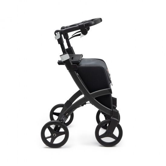 Rollator, schwarz, seitliche Ansicht. Vier Räder, Handgriffe, Sitzfläche und Tasche.