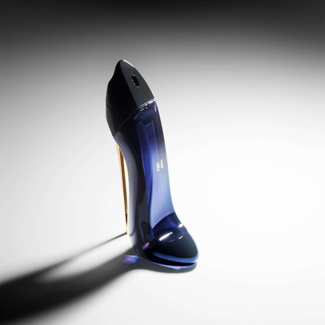 Blauer Flakon in Schuhform mit goldenem Absatz. Auf hellem Hintergrund.