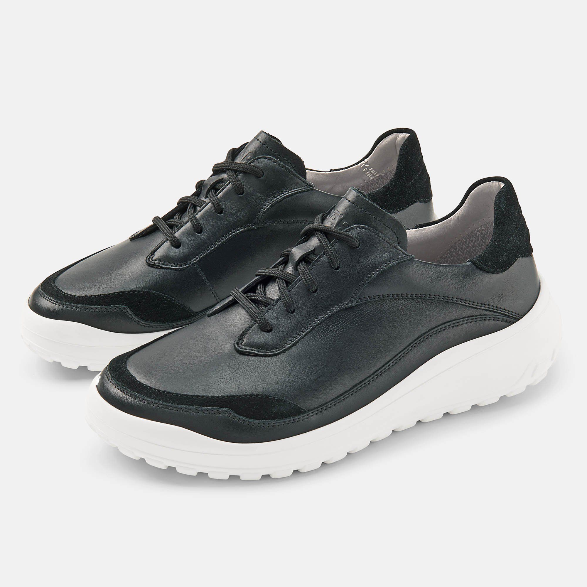 Paar schwarze Schnürschuhe mit weißer Sohle. Leder-Obermaterial, breite Passform. Schwarze Schnürsenkel.