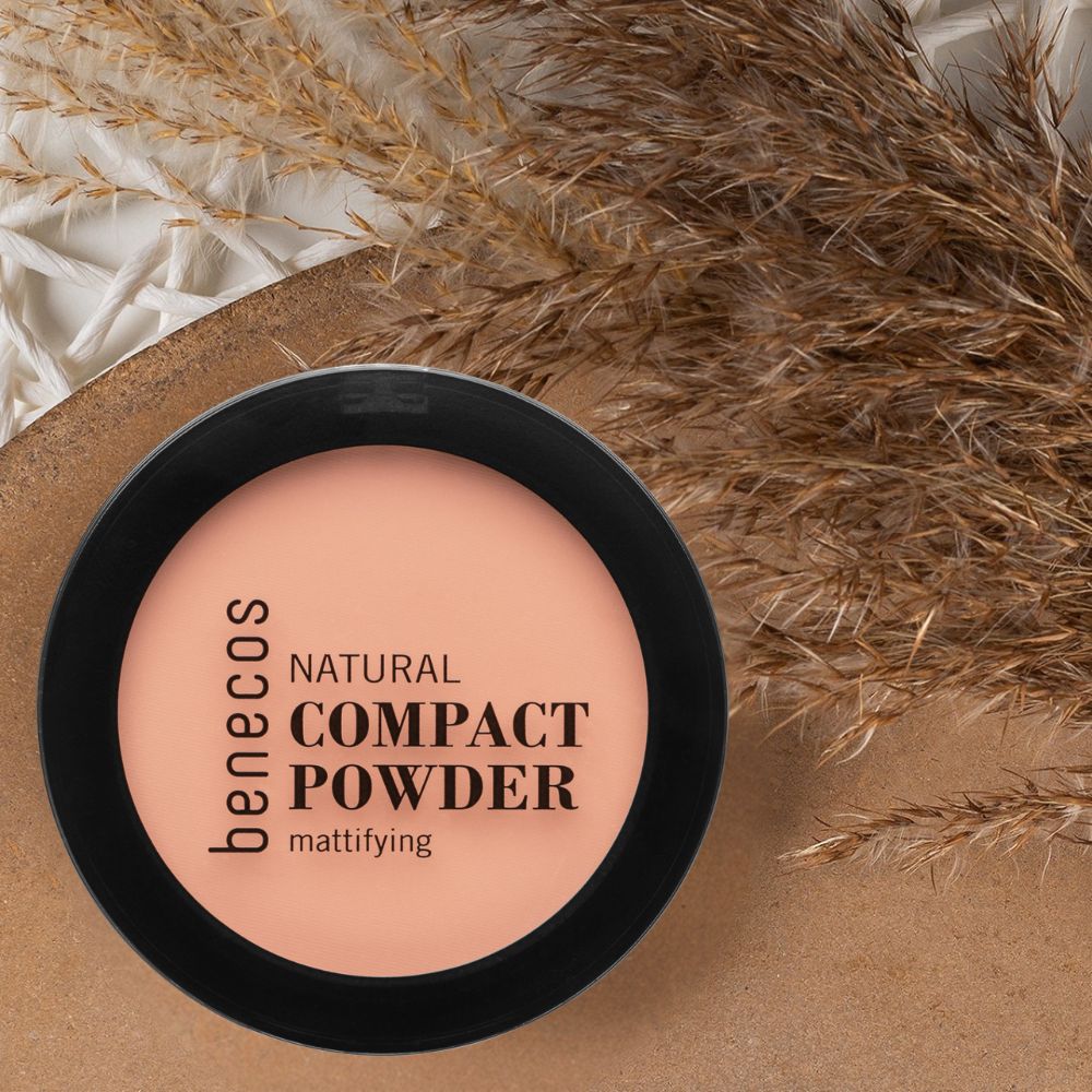 Benecos Natural Compact Powder mattierend in schwarzer Dose, neben getrockneten Gräsern.