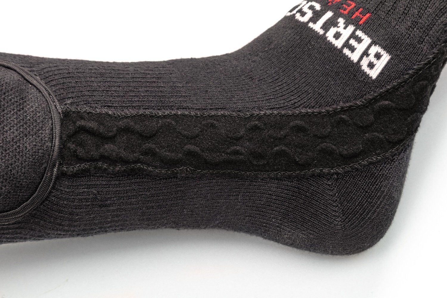 Nahaufnahme des Knöchels einer schwarzen BERTSCHAT® Socke. Ein geprägtes Muster ist zu sehen.