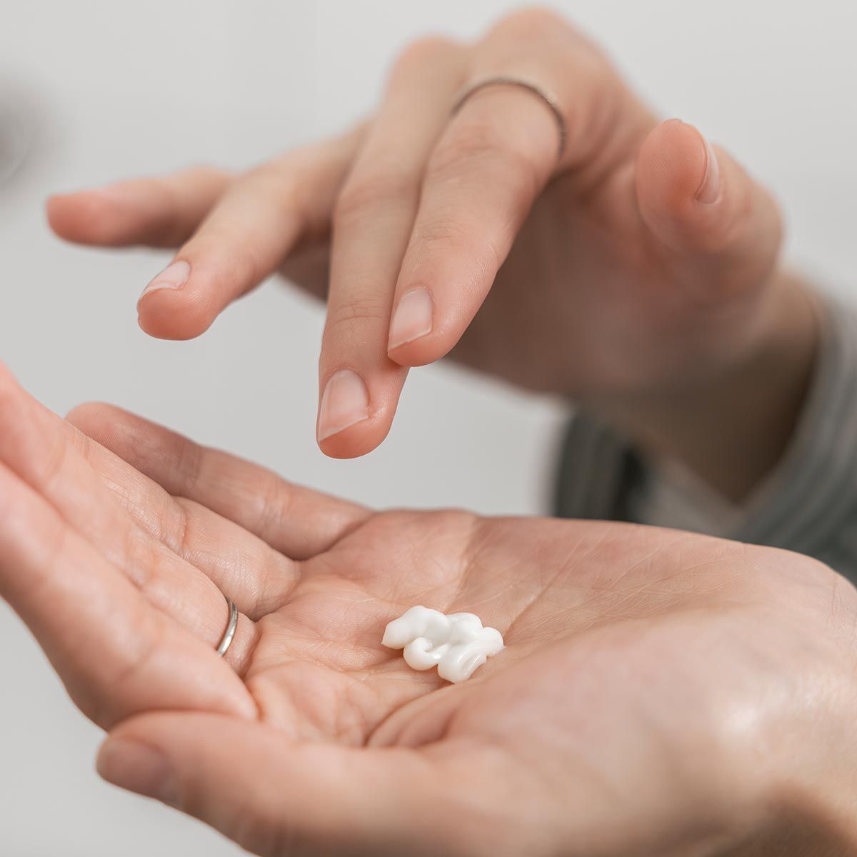Nahaufnahme einer Hand mit einem kleinen Klecks Creme. Eine andere Hand darüber.