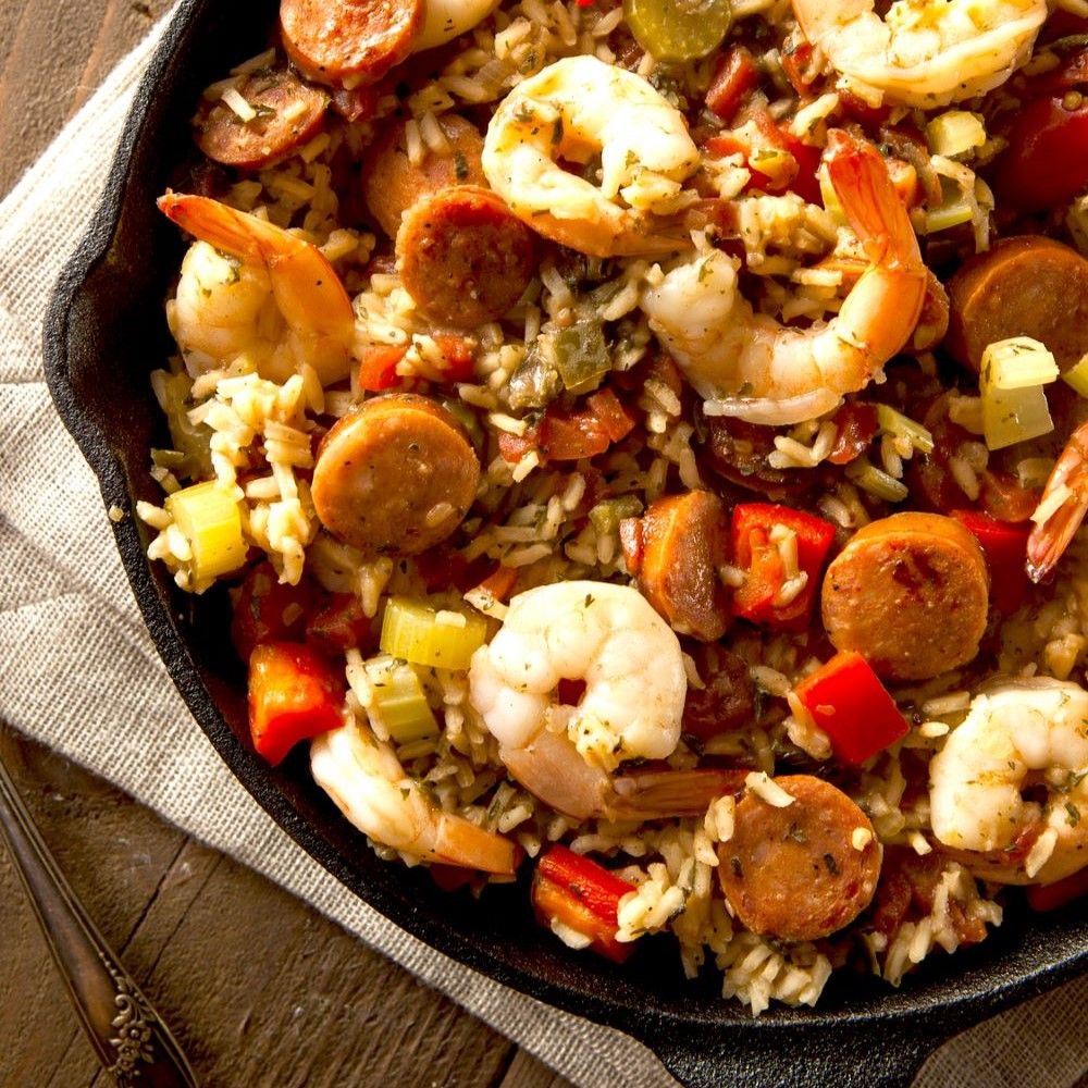 Pfanne mit Reis, Shrimps, Wurst und Gemüse. Nahaufnahme. Auf Leinentuch. Zutaten sichtbar.
