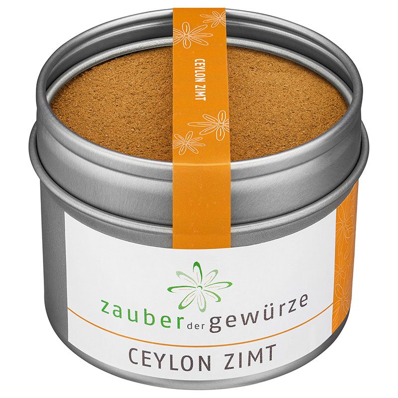 Runde Dose mit gemahlenem Zimt. Orangefarbener Aufkleber mit Text: Ceylon Zimt. Weißes Etikett mit Text: Zauber der Gewürze, Ceylon Zimt.