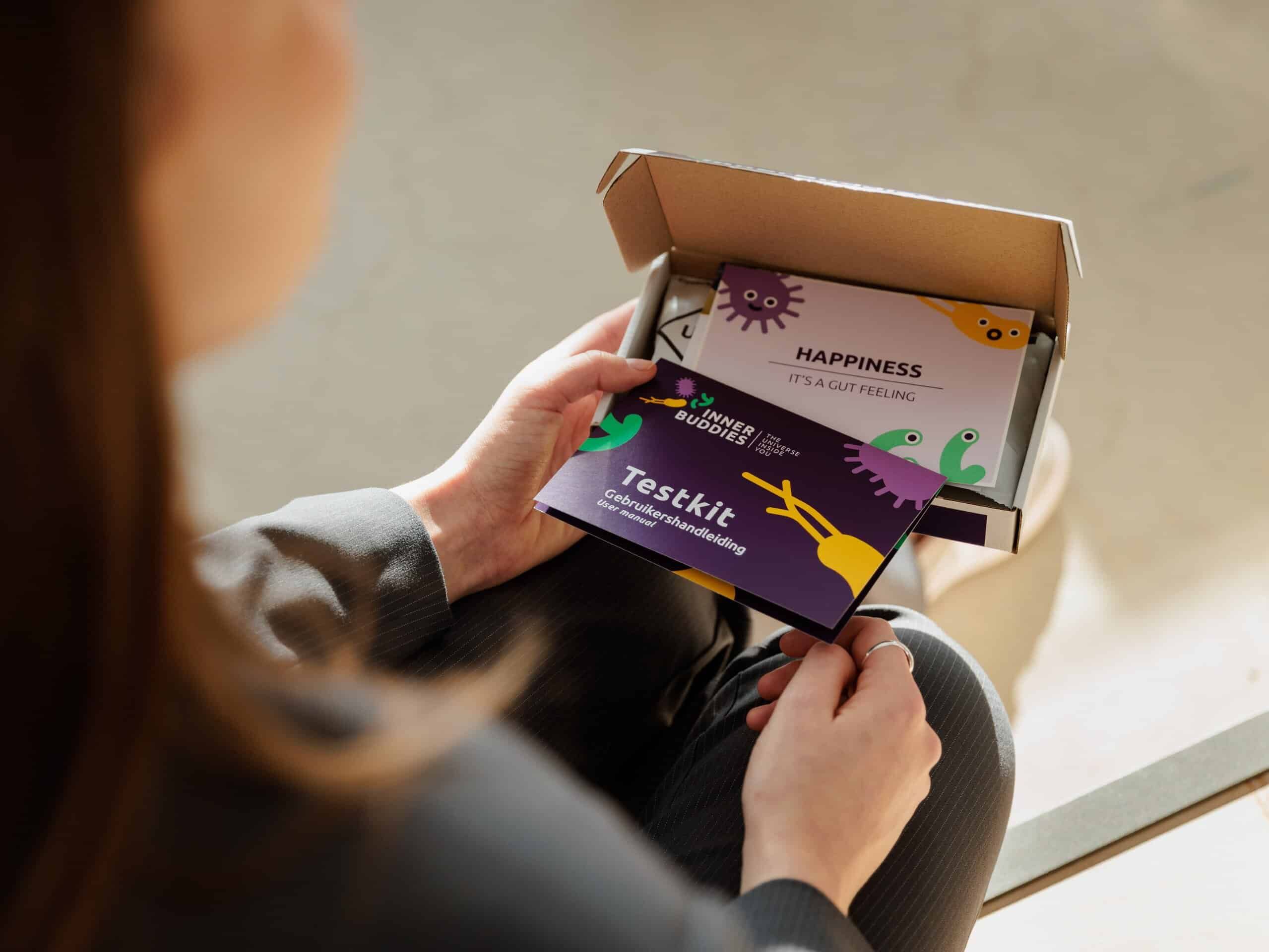 Person hält eine Inner Buddies Testkit-Karte mit der Aufschrift 'Testkit Mikrobiom-Empfehlung'.