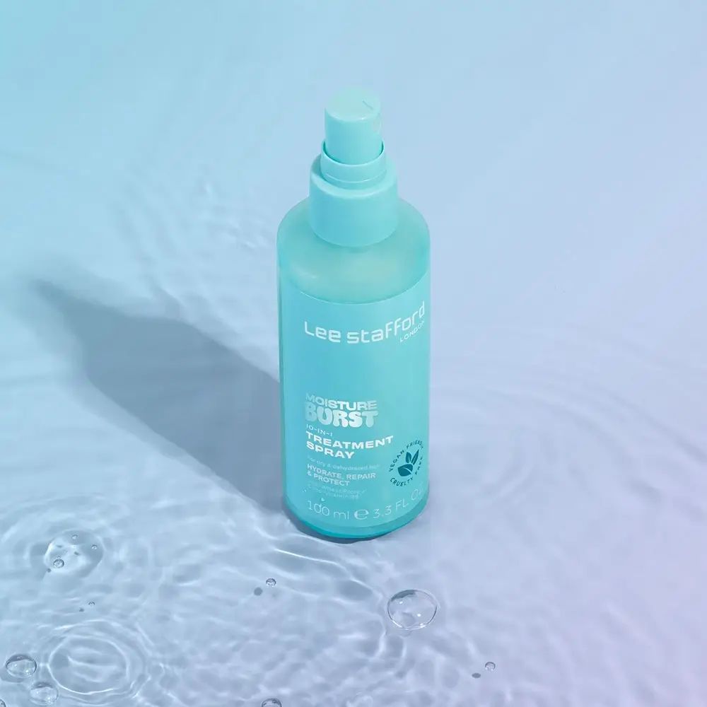 Türkisgrüne Sprühflasche auf einer Wasseroberfläche. Aufschrift: Lee Stafford, Moisture Burst, 10-in-1 Treatment Spray. Vegan-Logo.