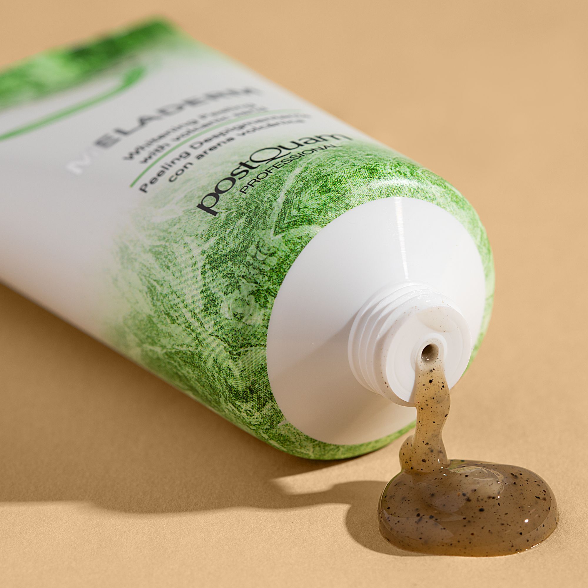 Weiße Tube, grüne Aufschrift. Produkt wird aus der Öffnung gedrückt. Text: MELADERM, Whitening Peeling with volcanic sand, postQuam PROFESSIONAL.