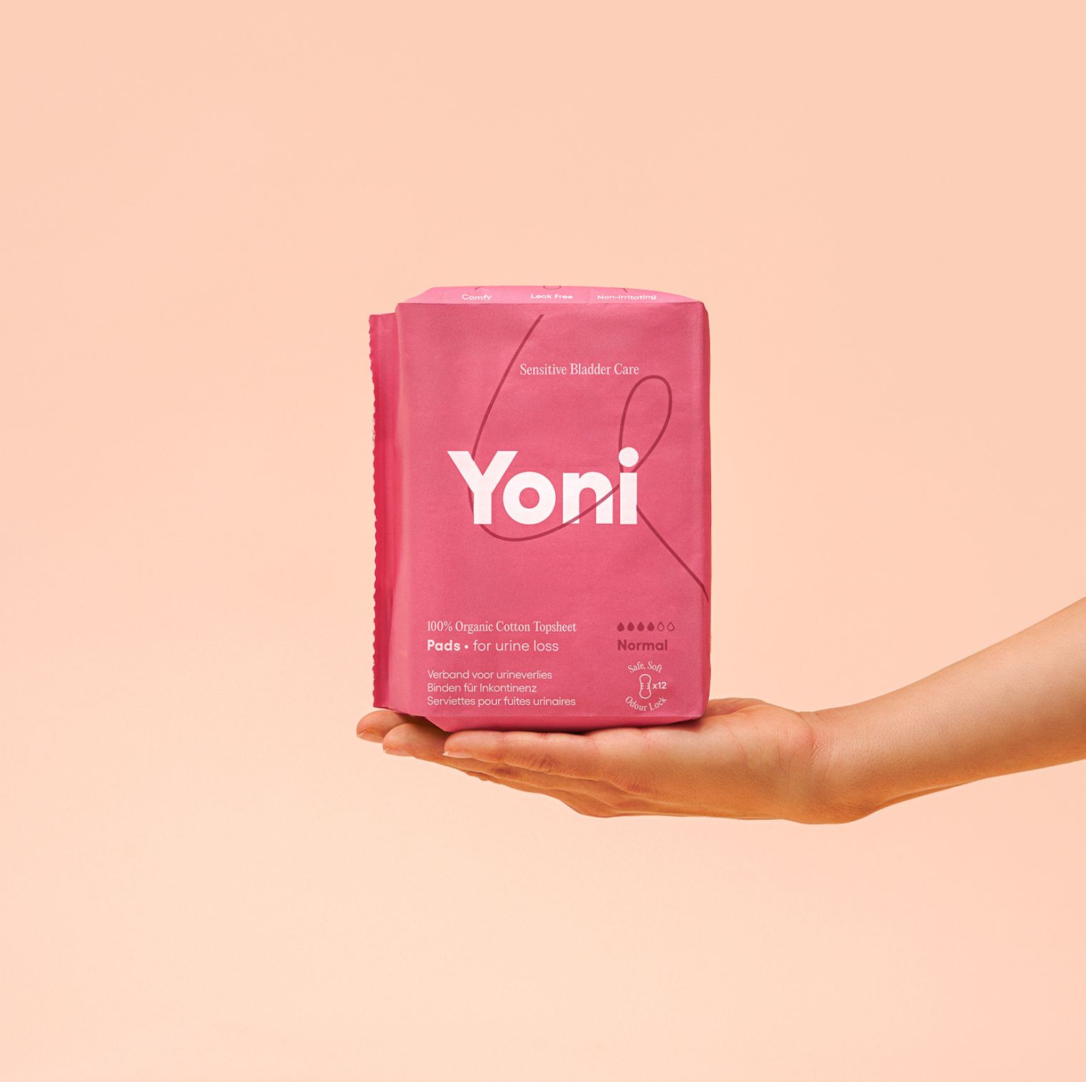 Rosa Verpackung mit Produkt. Aufschrift 'Yoni'. '100% Organic Cotton Topheet Pads for urine loss'. Gehalten von einer Hand.