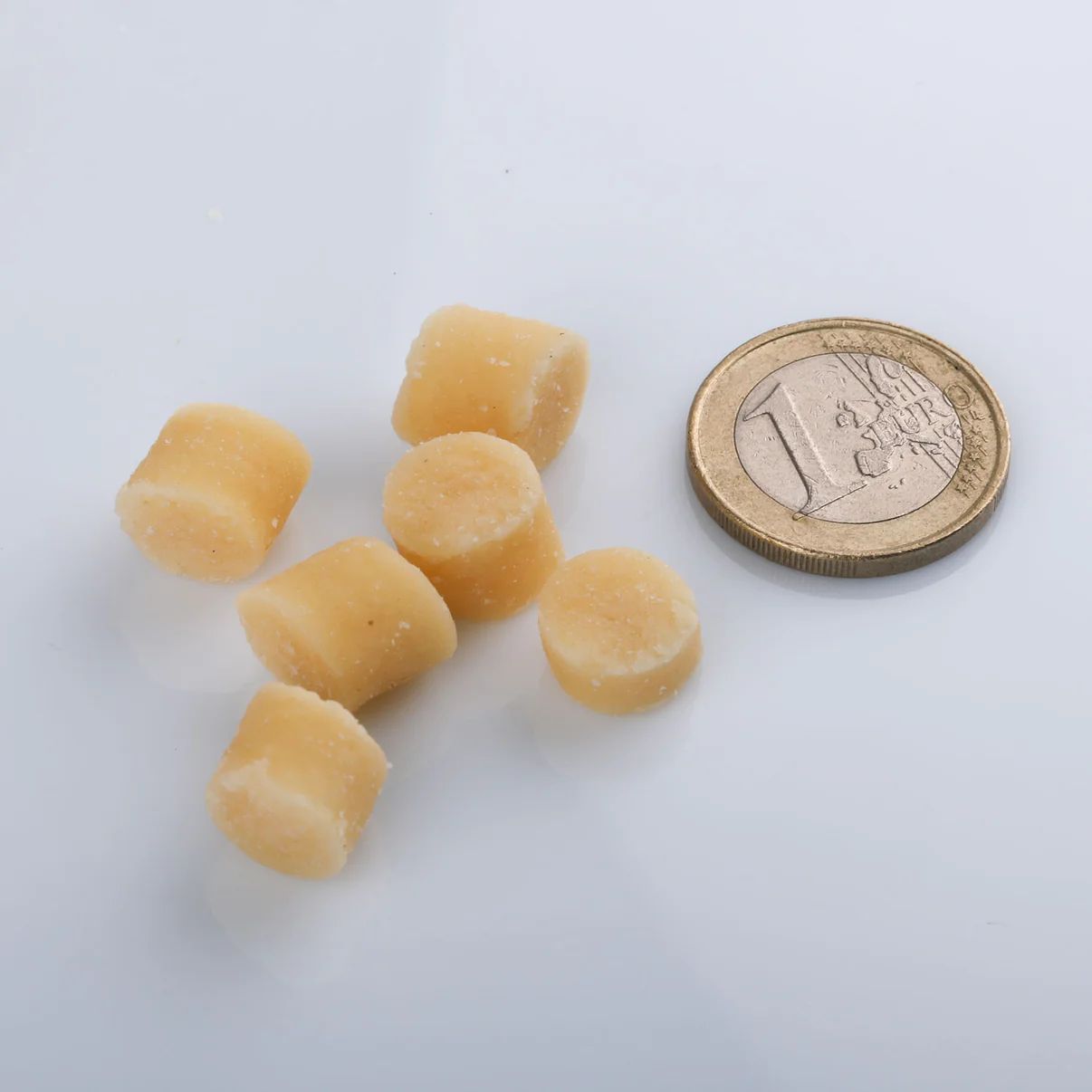 Sechs runde, helle Softies neben einer 1-Euro-Münze. Helle, runde Form.