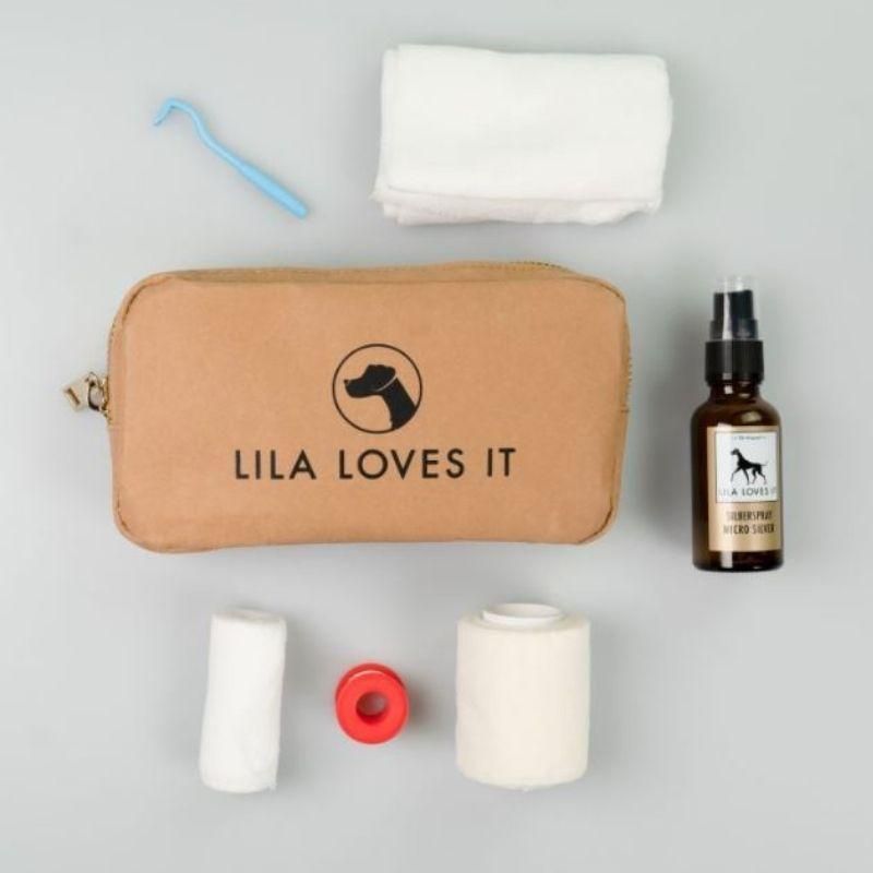 Erste Hilfe Tasche mit Inhalt: Verbandszeug, Spray, Zahnreiniger, Wattepads. Aufdruck: Logo und "LILA LOVES IT".