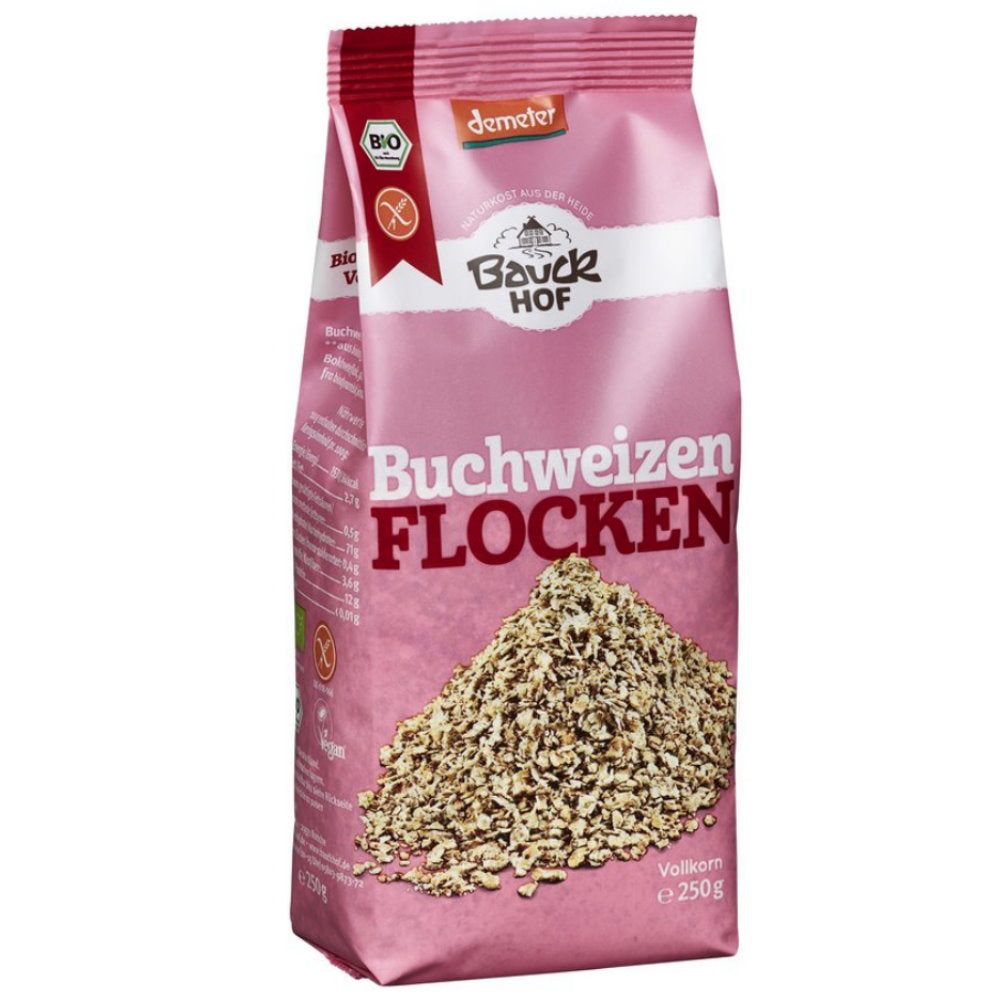 Rosa Beutel mit "Bauck Hof Buchweizen Flocken". Demeter-Siegel und glutenfrei-Symbol. Unten Flocken sichtbar.
