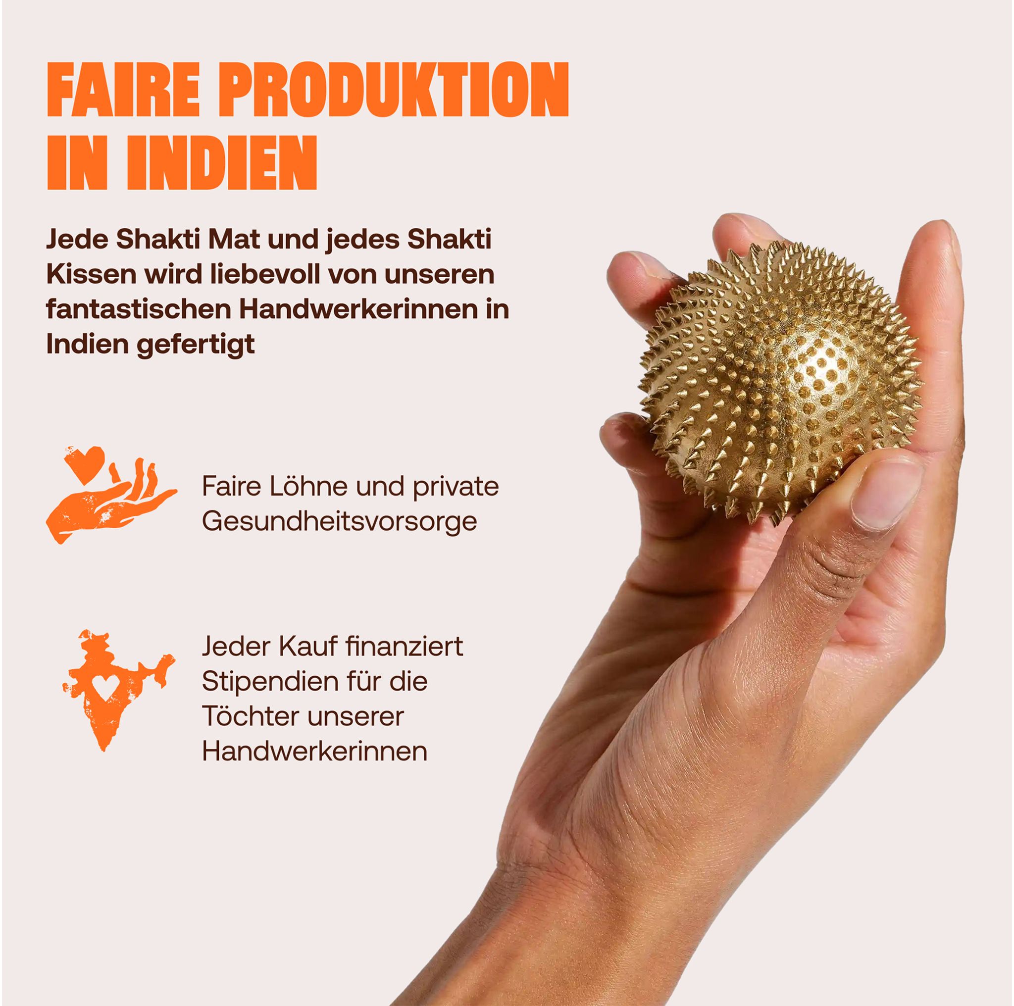 Hand hält einen goldenen Akupressurball mit vielen kleinen Spitzen.