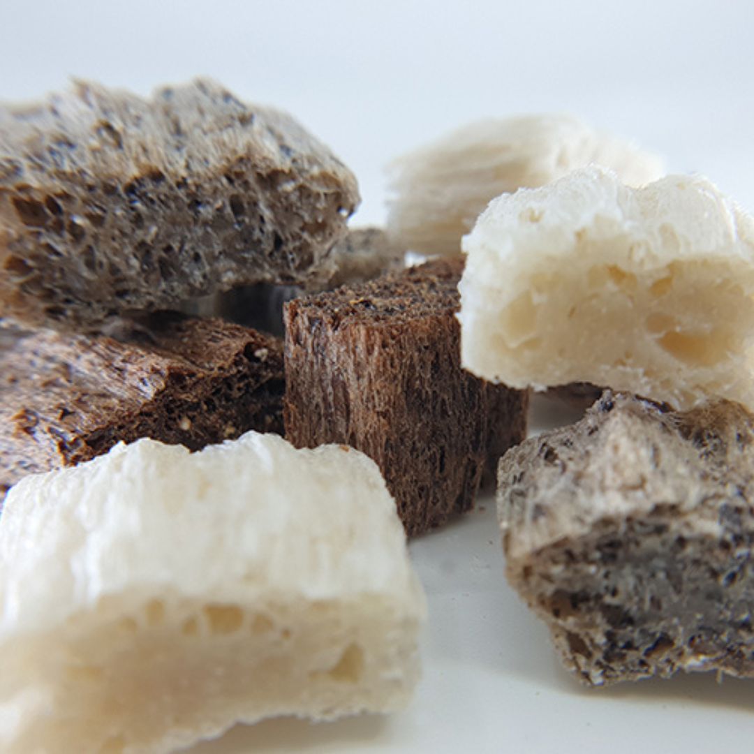 Verschiedenfarbige, unregelmäßig geformte Stücke. Einige sind hell, andere braun. Die Oberfläche ist porös.